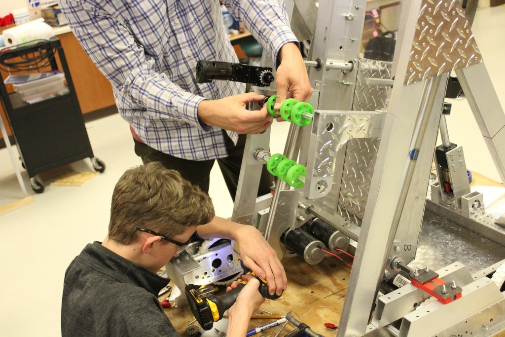 Students tightening bolts on a robot