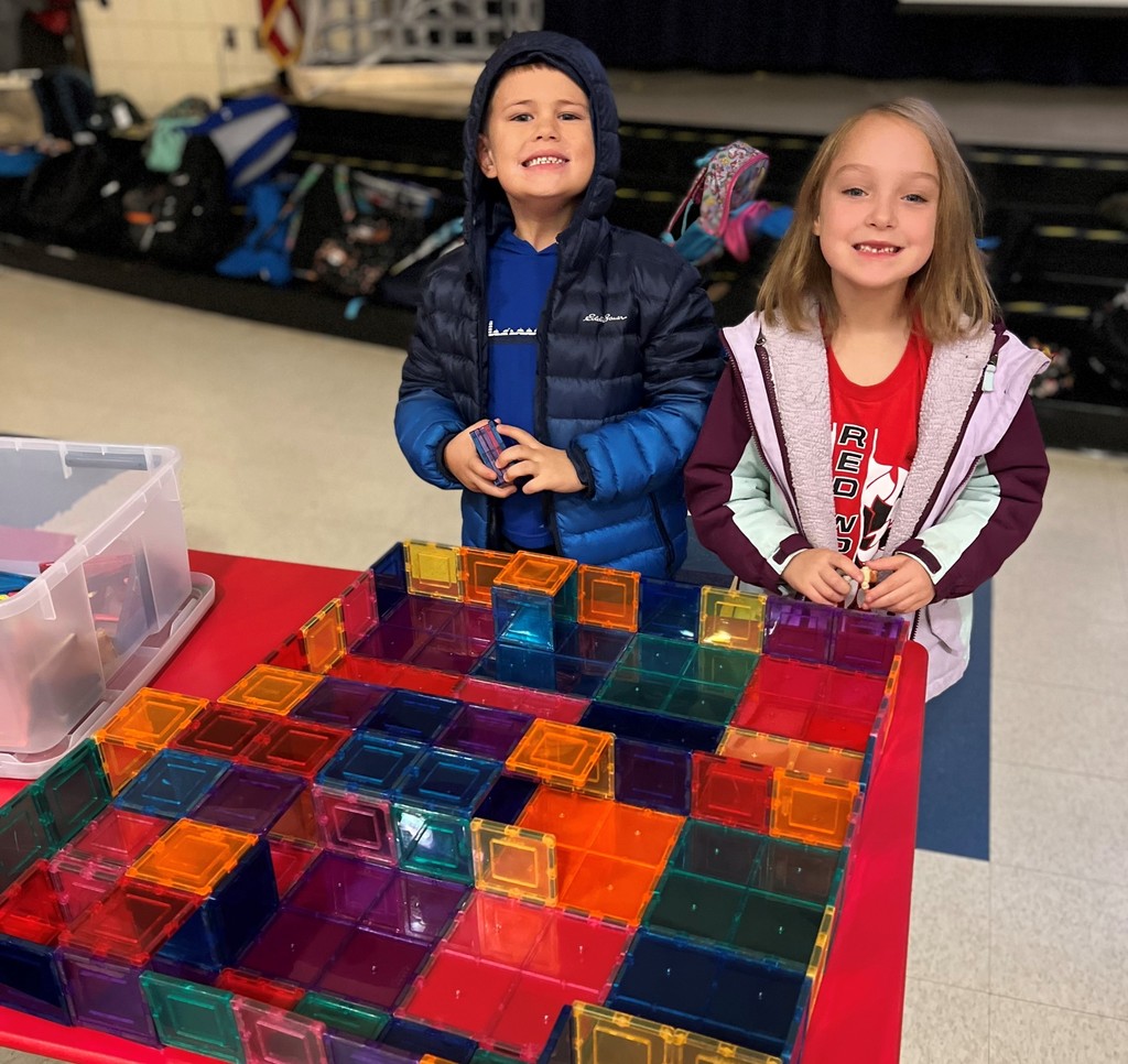 Two kids posing in front of lego blocks.