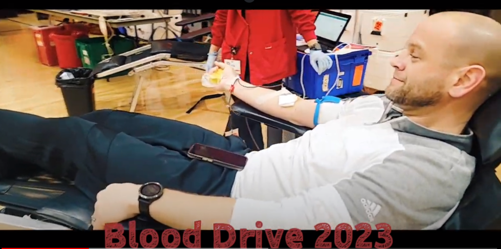 Man donating blood with Blood Drive 2023 under picture
