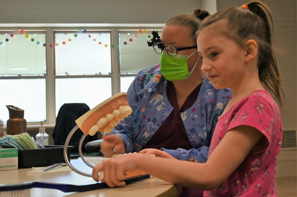 nurse checking girl's teeth in classroom