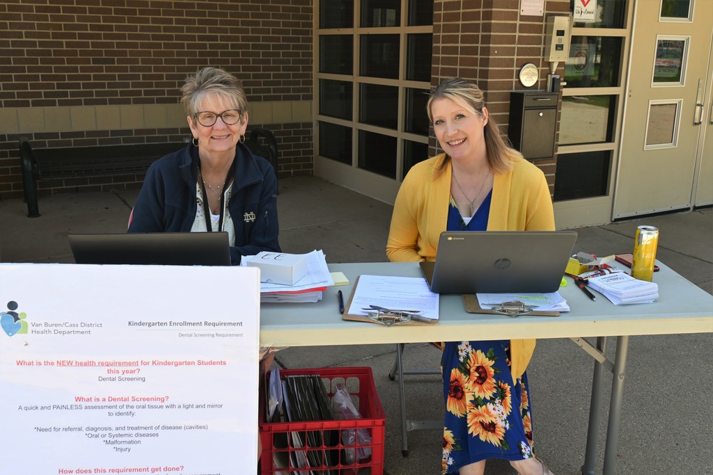 nurse and secretary seated in front of elementary school